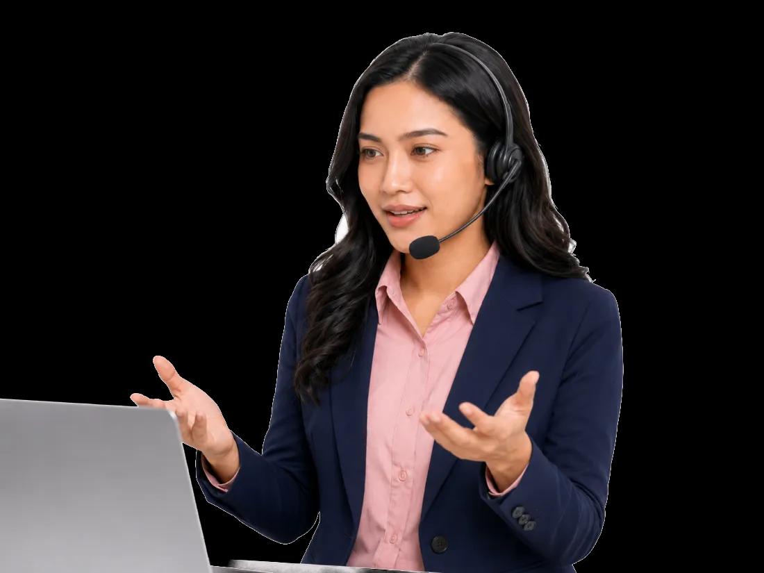 Agen contact center Lovina ber-headset berbicara dengan kedua tangan terbuka di depan laptop